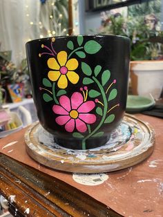 a painted flower pot sitting on top of a wooden table