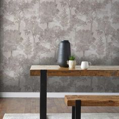 a table with two benches and a vase on it in front of a wallpapered background