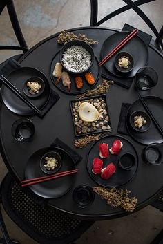 a black table topped with plates and bowls filled with different types of food on top of it