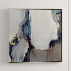 a painting hanging on the wall in an empty room with white walls and gold accents