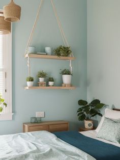 a bed room with a neatly made bed and two plant shelves on the wall above it