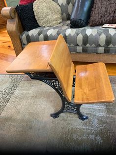 a wooden table sitting on top of a metal stand in front of a gray couch