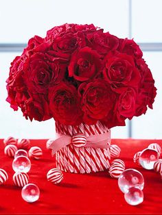 a vase filled with roses and candy canes on top of a red table cloth