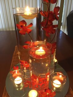 candles and flowers are arranged in glass vases on a table with a candle holder