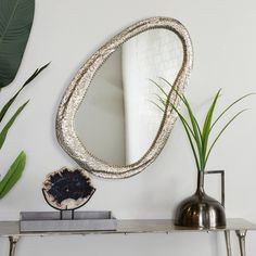 a mirror sitting on top of a table next to a potted plant and vase