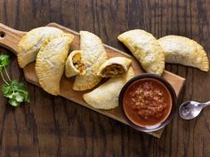 some food is laying out on a cutting board with a bowl of sauce next to it