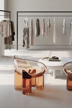 a white table and chairs in a room with clothes hanging on the rack behind them