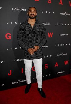 a man standing on top of a red carpet next to a black and white wall