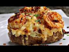 a white plate topped with a baked potato covered in cheese and shrimp