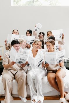 a group of people sitting on top of a bed holding up papers in the air