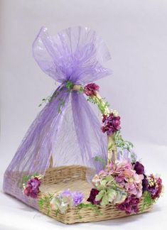 a wicker basket with flowers in it and a purple organ - net bag on top