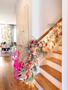 a decorated christmas tree sitting on top of a wooden floor next to a stair case