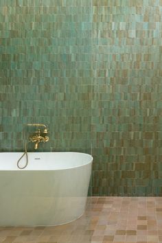 A bathroom features beige zellige tiles on the floor, with trapezoid-shaped turquoise tiles on the wall above a modern white bathtub. Trapezoid Zellige, Diy Tile Shower, Zia Tile, Dimensional Tile, Earthy Home Decor, Mid Century Modern Kitchen, Diy Tile, Classic Interior Design, Zellige Tile