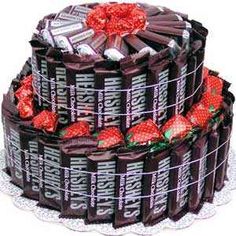 a large chocolate cake covered in wrappers and wrapped with red ribbon on a white plate