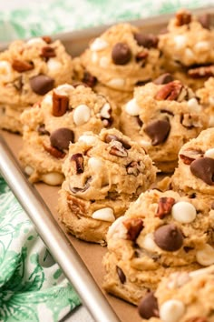 cookies with nuts and chocolate chips are on a baking sheet, ready to be eaten