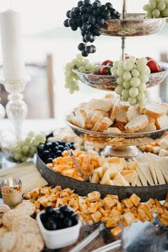 an assortment of cheeses, crackers and grapes on a table