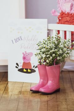 a pink boot with flowers in it sitting next to a card and flower pot on the floor