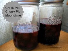 two jars filled with liquid sitting on top of a wooden table