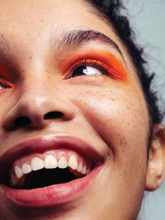 a woman with bright orange eyeshadow smiling