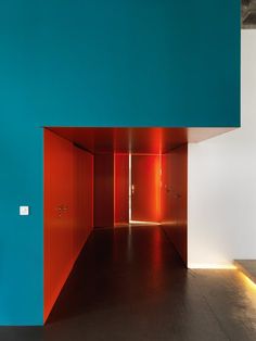 an empty room with blue walls and red doors in the center is lit by lights