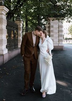 a bride and groom are standing in front of an iron fence