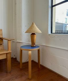 a lamp sitting on top of a wooden table next to a chair in a room