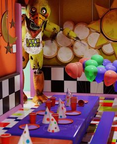 a table topped with lots of colorful balloons and paper hats next to a creepy monster