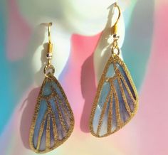 a pair of gold and blue earrings on top of a white mannequin