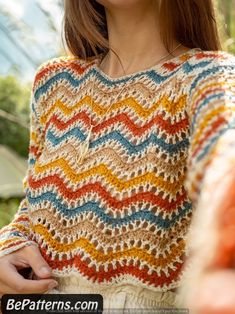 a woman wearing a multicolored crochet sweater