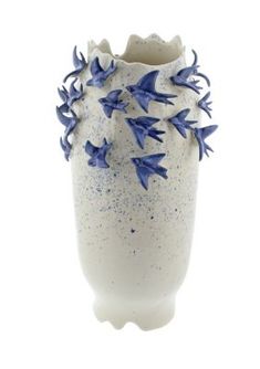 a white vase with blue flowers on the outside and inside, against a white background