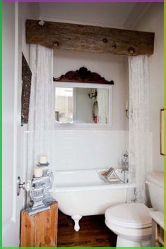 a white bath tub sitting next to a toilet in a bathroom under a wooden beam