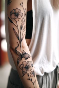 a woman's arm with flowers on it and a bird in the middle,