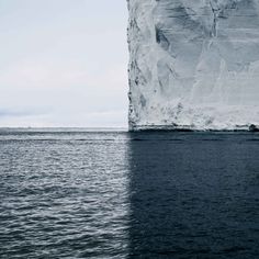 an iceberg in the middle of the ocean with water around it and snow on top