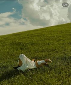 a woman laying in the grass on top of a hill