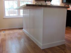 a kitchen island in the middle of a hardwood floor