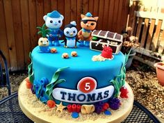 there is a blue cake decorated with animals and letters on the top, along with other decorations