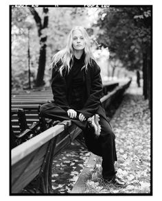 a black and white photo of a woman sitting on a bench