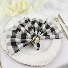 black and white checkered napkins on a plate with silverware next to flowers