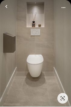 a white toilet sitting inside of a bathroom next to a wall mounted urinal and paper dispenser