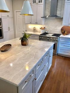 a large kitchen with white cabinets and an island countertop that has a potted plant on it