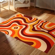 an orange, red and yellow area rug on the floor in front of a white chair