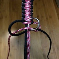 a pink and black rope tied up to a pole with a metal hook on it