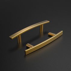 a pair of gold - plated metal handles on a black surface