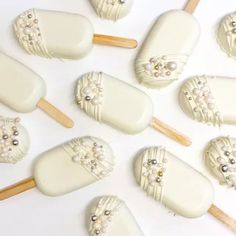 some white lollipops with pearls and bows on them are arranged in rows