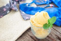 a glass filled with ice cream sitting on top of a wooden table next to a blue bag