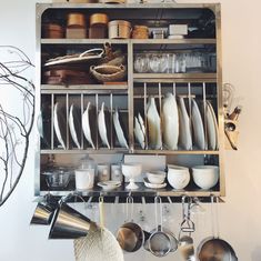 a shelf filled with lots of dishes and pans next to a wall mounted pot rack