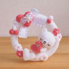 a white and pink crocheted bracelet with a teddy bear holding a heart on it