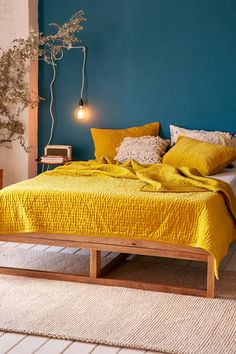 a bedroom with blue walls and yellow bedspread on the bed, next to a white rug