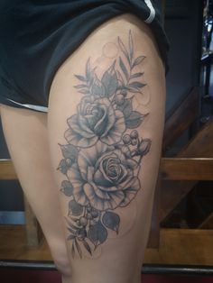 a woman's thigh with roses and leaves tattoo on the side of her leg