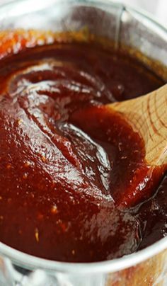 a wooden spoon in a pot filled with sauce